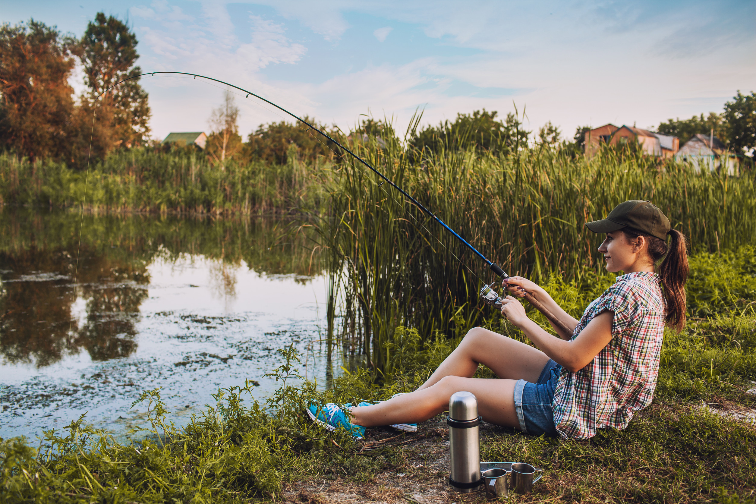 happy woman is fishing with rod on lake