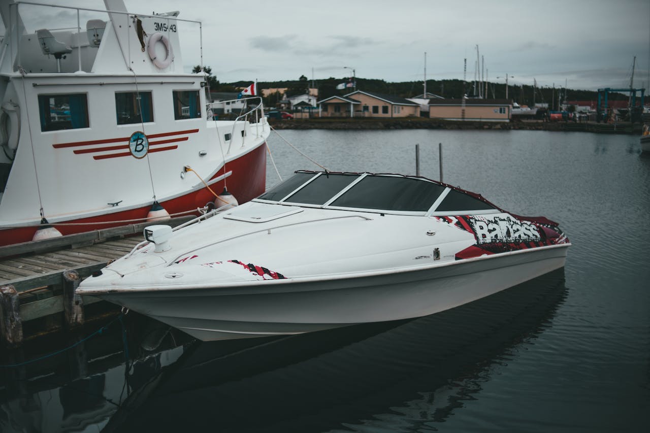 services-02 A sleek motorboat docked peacefully beside a larger boat in a quiet harbor setting.